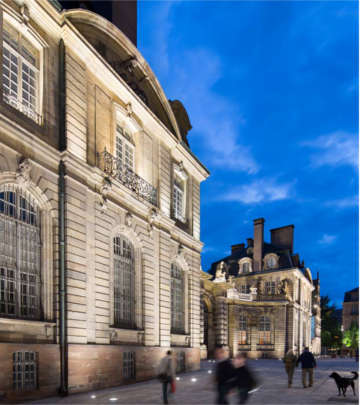Persone che osservano l'illuminazione dell'architettura davanti a un edificio nella Grand Île, Strasburgo, illuminata da Philips Lighting