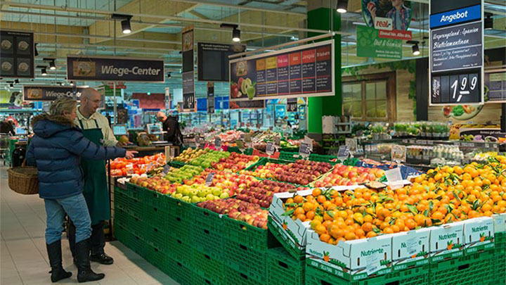 I clienti ammirano la frutta presso Real, illuminata con le soluzioni per supermercati di Philips