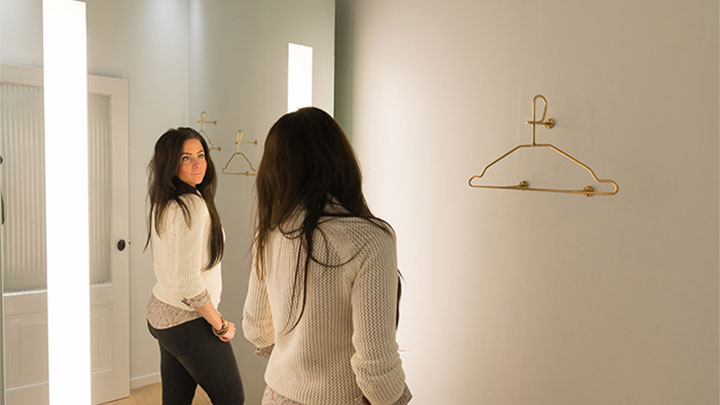 Una cliente di SuperTrash si guarda nello specchio AmbiScene di Philips, con la configurazione della luce "Giorno"