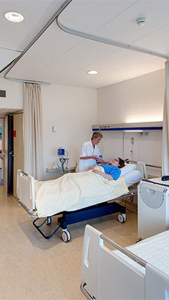 Un'infermiera controlla un paziente in una stanza del centro UMCG, illuminata con le soluzioni a risparmio energetico di Philips