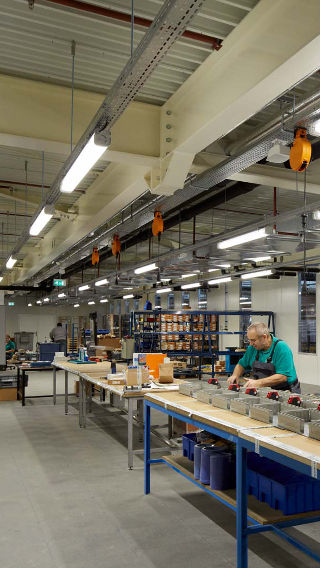 Dipendente al lavoro nell'area di produzione del Venco Campus, brillantemente illuminata con le soluzioni industriali di Philips