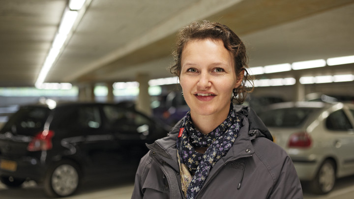  Donna sorridente davanti a una vettura nel parcheggio Eiteren illuminato da Philips Lighting 