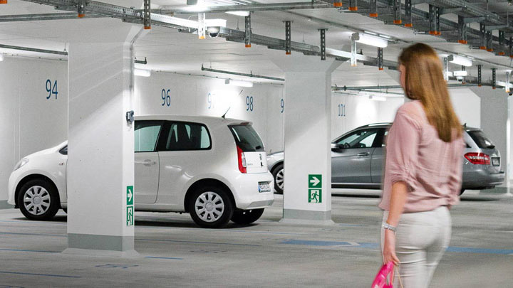 Una donna cammina verso la sua auto in un parcheggio sotterraneo ben illuminato 