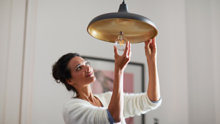 Donna che avvita una lampada di largo consumo in casa