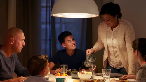 Famiglia che mangia attorno a un tavolo ben illuminato