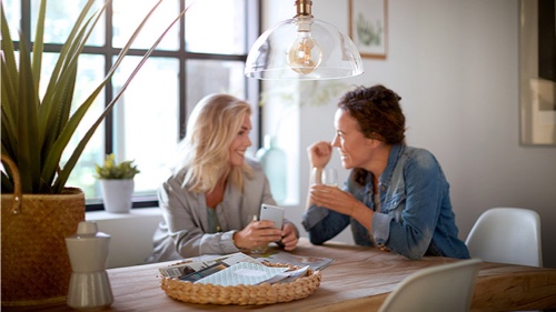 Due donne a casa che parlano illuminate da una lampada Philips