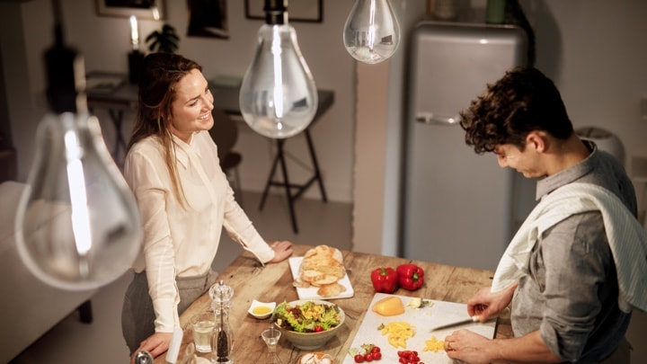 Un uomo e una donna dall'alto che preparano le cena in una cucina ben illuminata