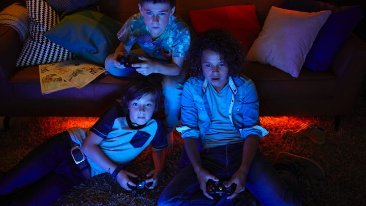 3 ragazzi giocano a videogame con un'illuminazione d'atmosfera