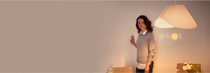 Donna che regola l'interruttore dimmer intelligente, controllando l'atmosfera calda dell'illuminazione LED in uno spazio abitativo contemporaneo con arredamento minimalista