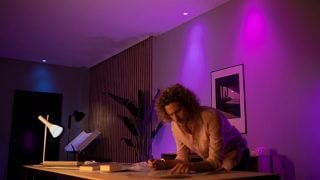 Le luci LED Philips Hue creano un'atmosfera vivace nei toni del porpora e del Rosa nel soggiorno, creando un'illuminazione d'atmosfera personalizzabile per le serate cinema e il relax nelle case moderne.