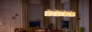 La moderna lampada a sospensione a LED con più paralumi in tessuto illumina un accogliente soggiorno, proponendo soluzioni di illuminazione domestica eleganti e a risparmio energetico per un comfort ambientale nelle ore serali.