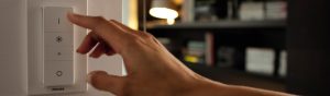 "Regolazione manuale del dimmer LED Philips, per controllare l'illuminazione ambientale in un accogliente soggiorno con librerie."