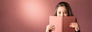 "Una bambina sbircia un libro rosa su uno sfondo illuminato a LED, che crea un'illuminazione calda e uniforme, ideale per una lettura confortevole."