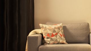 "Accogliente soggiorno con moderna lampada da tavolo LED, che illumina il divanetto grigio e crea un'atmosfera calda per il relax domestico."