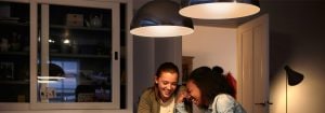 "Le moderne lampade LED a sospensione creano un'atmosfera calda per due donne che conversano, dimostrando soluzioni di illuminazione domestica a efficienza energetica."