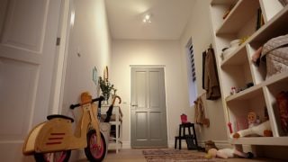Ingresso luminoso con faretti LED da incasso che illuminano scaffali, giocattoli e una bicicletta senza pedali per bambini.