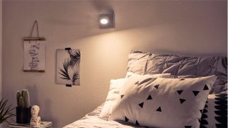 Elegante camera da letto con faretto spot LED ad alta potenza orientabile che crea un'atmosfera accogliente, illuminando la biancheria da letto geometrica e l'arredamento minimalista.