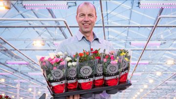 Leo van der Harg is posing with colorful flowers in his hands.