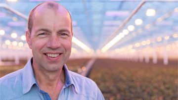 Leo van der Harg posing in his greenhouse lit by Philips lighting